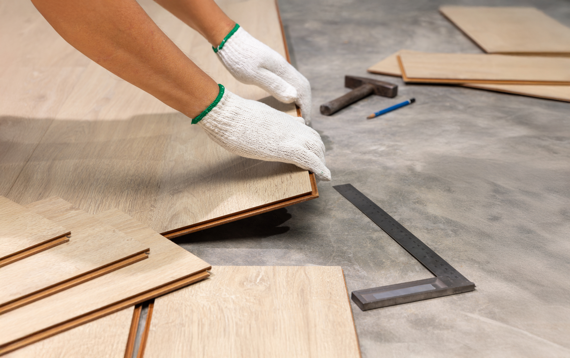 worker installing interlocking laminate floor, home renovation.